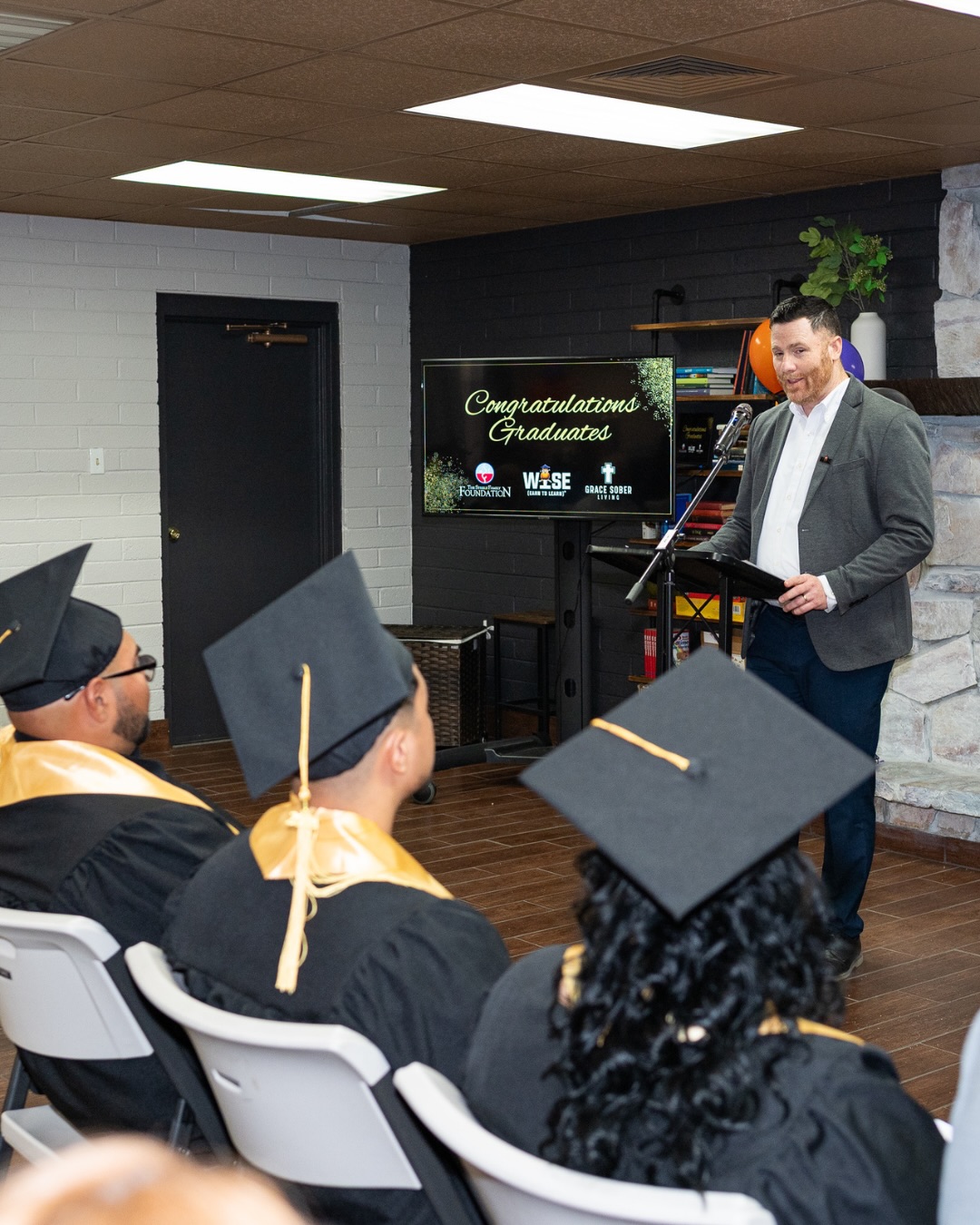 A speaker addresses seated graduates during the WISE celebration.